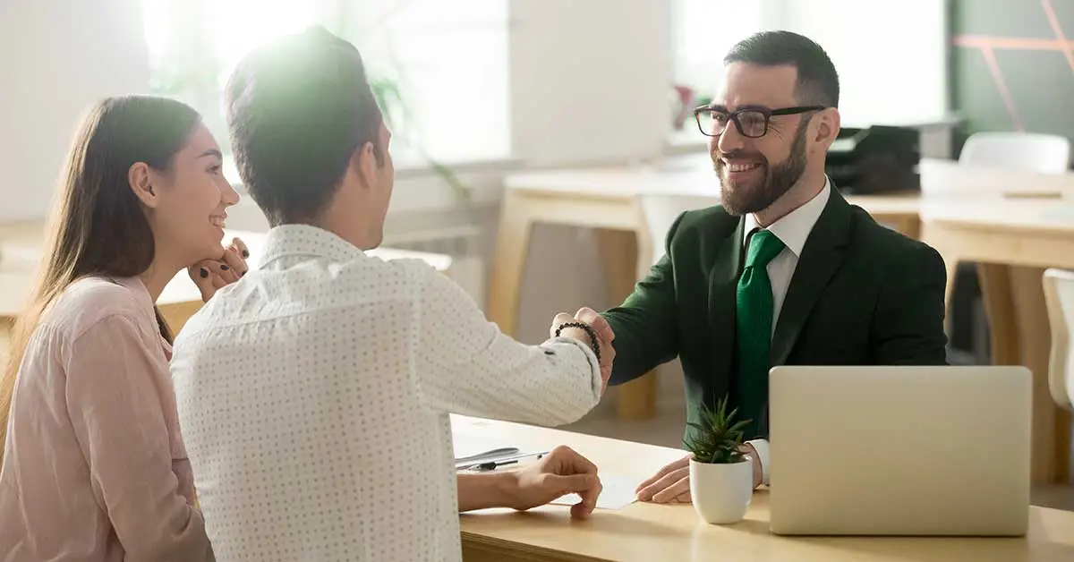 Un conseiller INTERNATIONALE BANQUE accueille des clients avec le sourire.