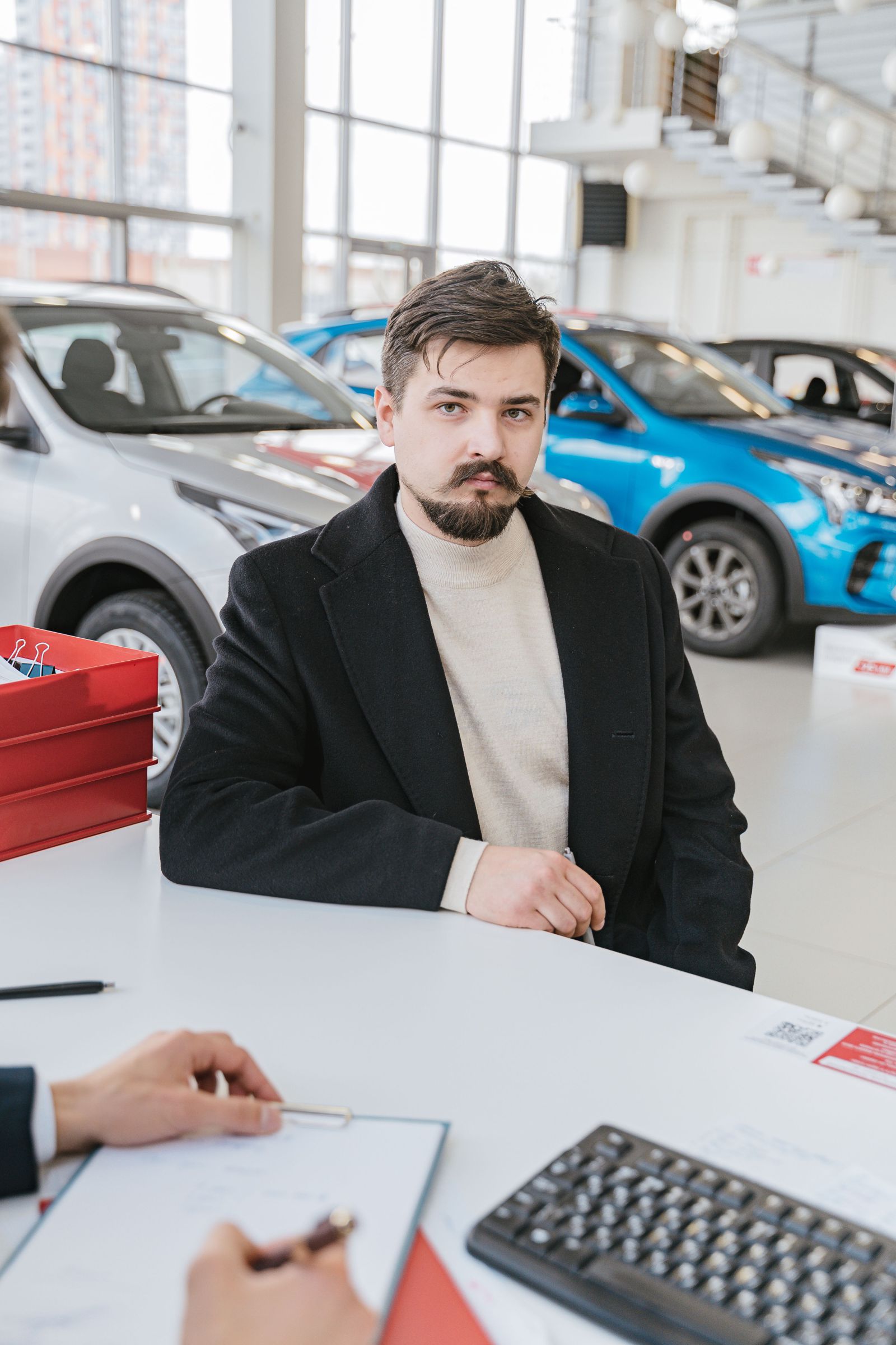 Client signant un dossier de financement dans une concession automobile.