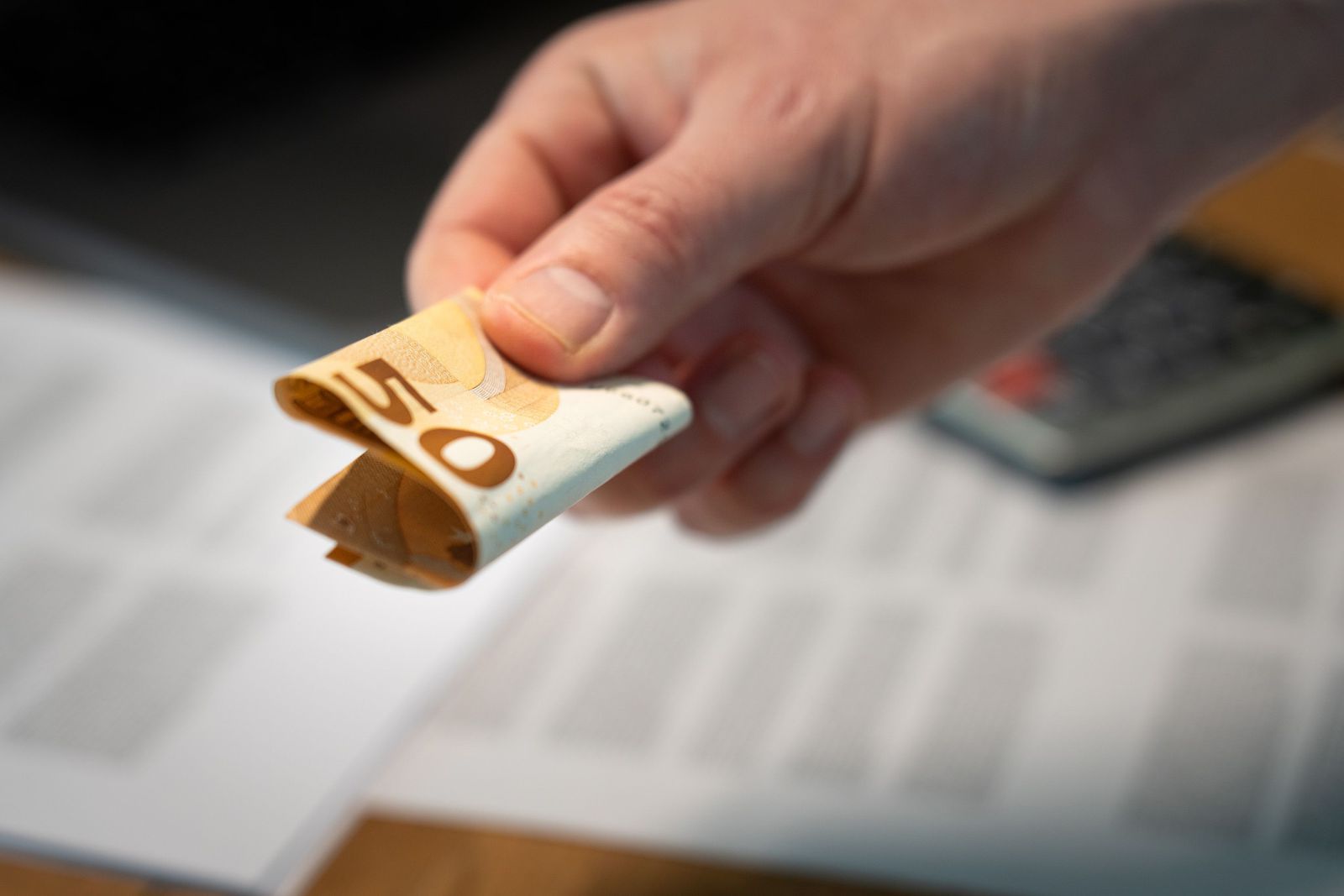 Simulation de financement : billets, documents et calculatrice sur un bureau.